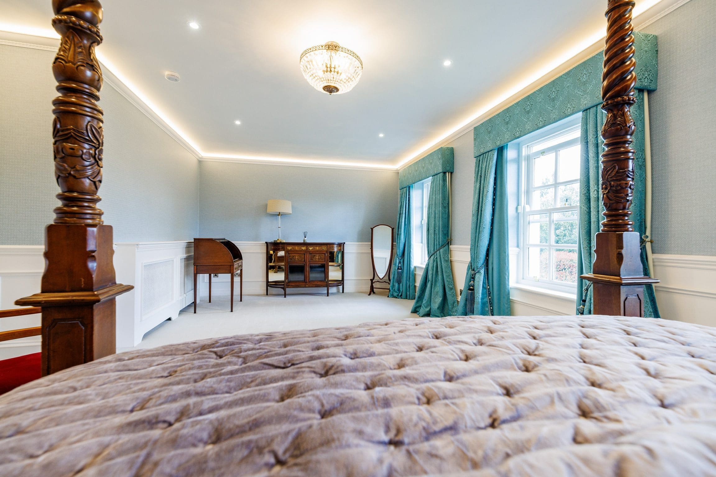 View from a bed in a bedroom suite with curtains and a desk.