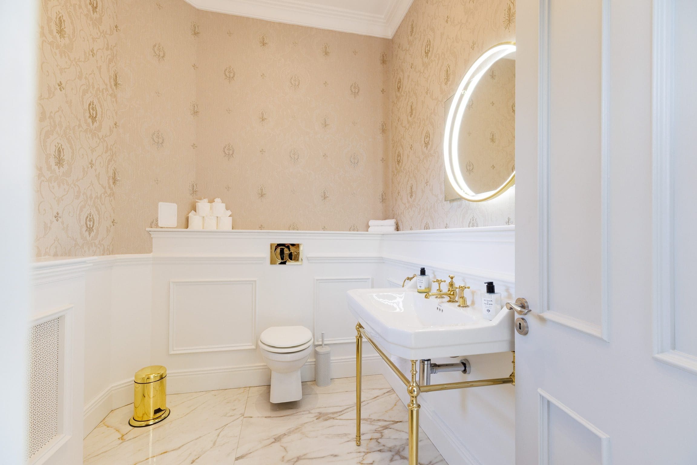gold bathroom fitting wood panelling and white marble floor