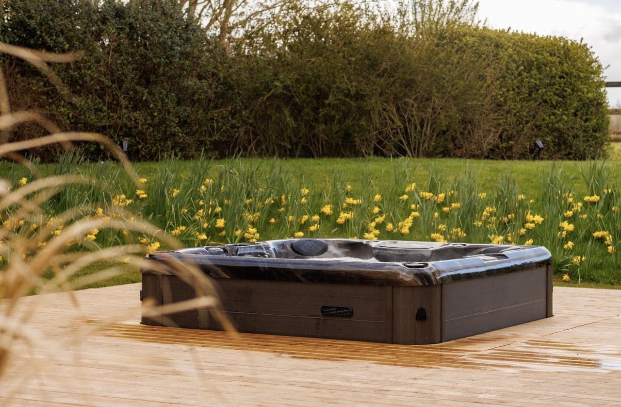 An outdoor 87 jet jacuzzi surrounded by garden flowers at Rochtaine Mansion