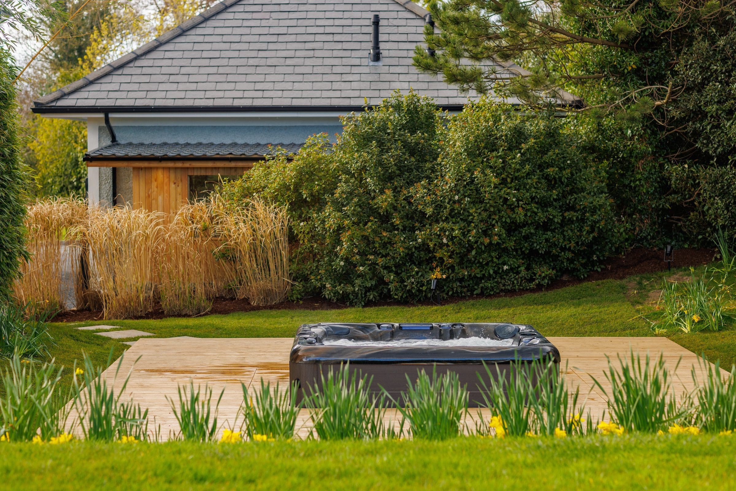 A hot tub jacuzzi surrounded by garden flowers at Rochtaine Mansion.